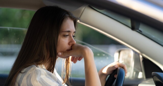 運転席で悩む女性